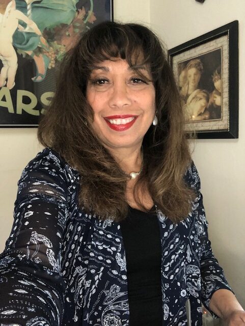 A woman with long hair and red lipstick smiles for the camera.